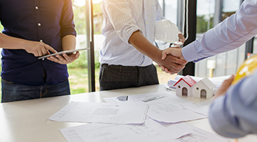 an image of a group of people around a table and two people shaking hands