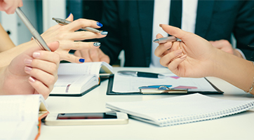 an image of a people around the table discussing with hand movements 