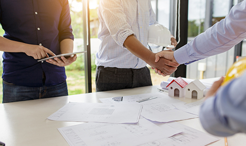 a picture of a group of people around the table and two of them are shaking hands 