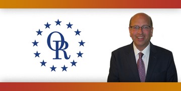 ORT logo with image of smiling bald man with glasses, wearing suit.