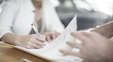 Close-up of a person signing a document.