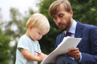 A man holding a document up for a toddler to write on.