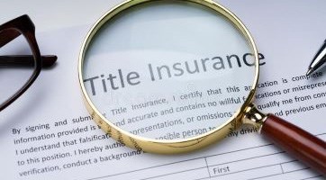 A magnifying glass sitting on top of a document that says "Title Insurance."